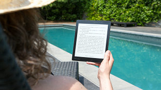 woman holding ebook by pool